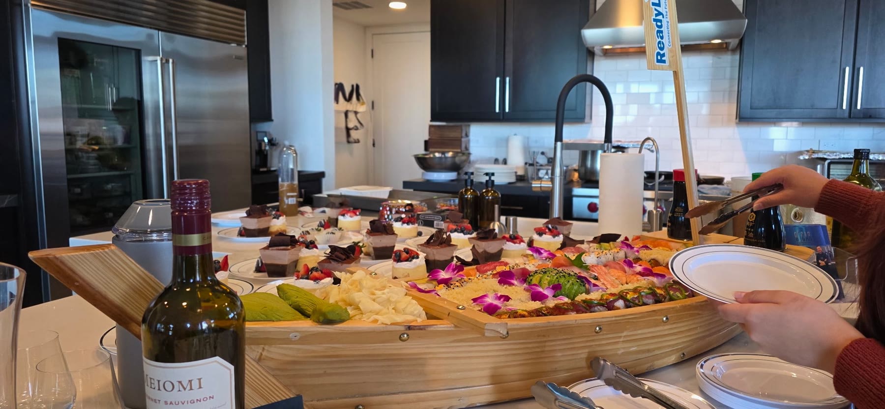 Sushi boat and mini desserts set up on a kitchen island for an in-home event