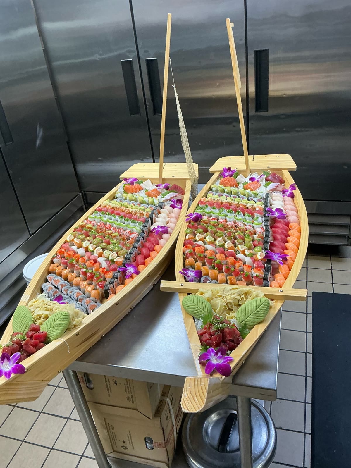 Two wooden sushi boats filled with specialty rolls, nigiri and sashimi